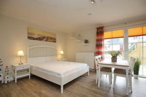 a bedroom with a white bed and a table and chairs at Strandvilla Krabbe Wohnung 08 in Boltenhagen