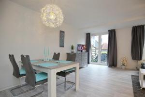 a dining room with a table and chairs and a chandelier at Sünnslag Wohnung 115 in Boltenhagen