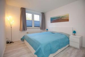 a bedroom with a blue bed and a window at Sünnslag Wohnung 115 in Boltenhagen