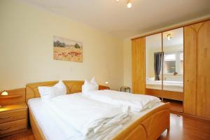 a bedroom with a large white bed and a mirror at Malaga Wohnung 3 in Boltenhagen