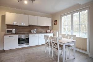 a kitchen with white cabinets and a table and chairs at Strandvilla Krabbe Wohnung 12 in Boltenhagen