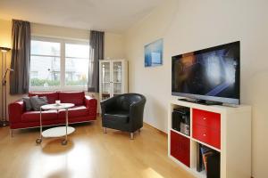 een woonkamer met een rode bank en een flatscreen-tv bij Dünenblick Wohnung 35 in Boltenhagen