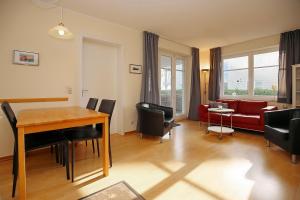 a living room with a table and a red couch at Dünenblick Wohnung 35 in Boltenhagen