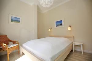 a bedroom with a white bed and a chair at Villa Triton Wohnung 01 in Boltenhagen