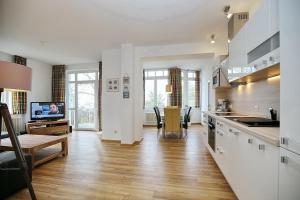 a kitchen with white cabinets and a living room at Villa Triton Wohnung 03 in Boltenhagen