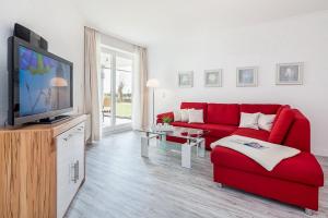 a living room with a red couch and a tv at Dünenblick Wohnung 22 in Boltenhagen