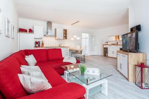 a living room with a red couch and a kitchen at Dünenblick Wohnung 22 in Boltenhagen