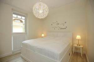 1 dormitorio con cama blanca y lámpara de araña en Strandvilla Scholle - Lachs Wohnung 01, en Boltenhagen