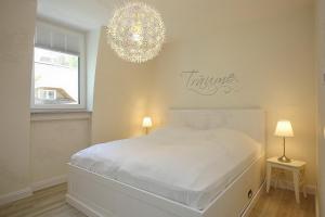 a white bedroom with a white bed and a chandelier at Strandvilla Scholle - Hering Wohnung 03 in Boltenhagen