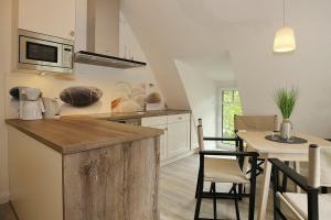 a kitchen with a counter and a table with chairs at Strandvilla Scholle - Scholle Wohnung 05 in Boltenhagen