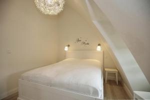 a bedroom with a white bed and a chandelier at Strandvilla Scholle - Aal Wohnung 06 in Boltenhagen