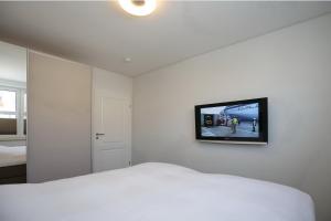 una camera con letto bianco e TV a parete di Sünnslag Wohnung 063 a Boltenhagen