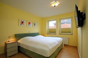 a yellow bedroom with a bed and a television at Goosbrink Wohnung 08 in Boltenhagen