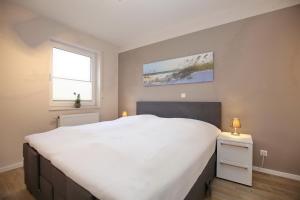 a bedroom with a large white bed and a window at Malaga Wohnung 1 in Boltenhagen