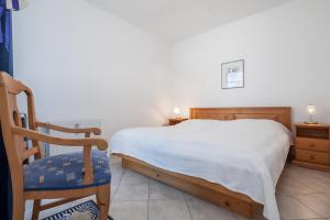 a bedroom with a white bed and a wooden chair at Dünenblick Wohnung 33 in Boltenhagen