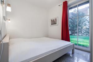 a white bedroom with a bed and a window at Strandvilla Niklot Wohnung 02 in Boltenhagen