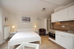 a bedroom with a white bed and a kitchen at Strandvilla Krabbe Wohnung 11 in Boltenhagen