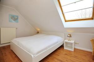 ein Schlafzimmer mit einem weißen Bett und einem Fenster in der Unterkunft Papillon Wohnung 10-6 in Boltenhagen