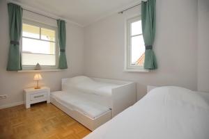 a bedroom with two beds and two windows at Likedeeler II Wohnung 04 in Boltenhagen
