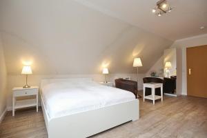 ein Schlafzimmer mit einem weißen Bett und ein Wohnzimmer in der Unterkunft Strandvilla Krabbe Wohnung 13 in Boltenhagen