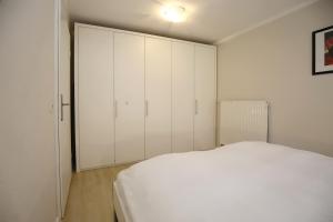 a bedroom with a white bed and white cabinets at Papillon Wohnung 15-2 in Boltenhagen