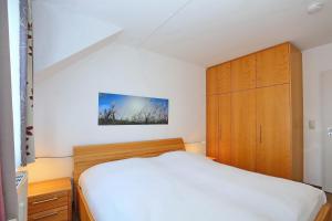 a bedroom with a white bed and a wooden cabinet at Haffblick Wohnung 11 in Boltenhagen