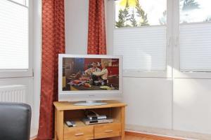 a television on a wooden stand in a room with windows at Goosbrink Wohnung 14 in Boltenhagen