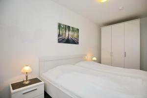 ein weißes Schlafzimmer mit einem weißen Bett und Schränken in der Unterkunft Sünnslag Wohnung 041 in Boltenhagen