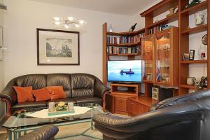 a living room with a leather couch and a television at Haffblick Wohnung 01 in Boltenhagen
