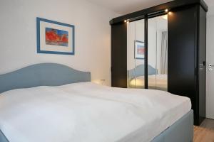 a bedroom with a white bed and a mirror at Haffblick Wohnung 01 in Boltenhagen
