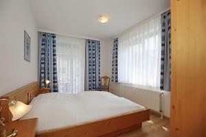 a bedroom with a large white bed and windows at Dünenblick Wohnung 43 in Boltenhagen