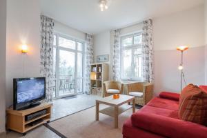 a living room with a red couch and a tv at Villa Triton Wohnung 02 in Boltenhagen