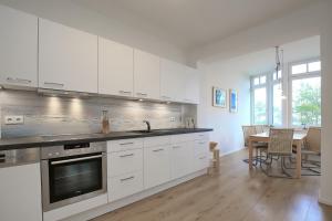 a kitchen with white cabinets and a dining room with a table at Villa Triton Wohnung 04 in Boltenhagen