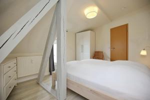 a bedroom with a large white bed and a staircase at Villa Triton Wohnung 06 in Boltenhagen