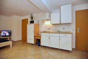 a kitchen with white cabinets and a tv in a room at Villa Triton Souterrain Wohnung 09 in Boltenhagen