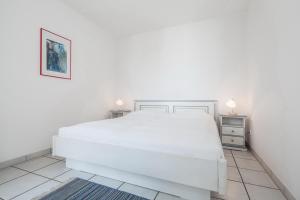 a white bed in a white bedroom with two night stands at Dünenblick Wohnung 50 in Boltenhagen