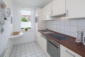 a white kitchen with a sink and a stove at Sünnslag Wohnung 012 in Boltenhagen