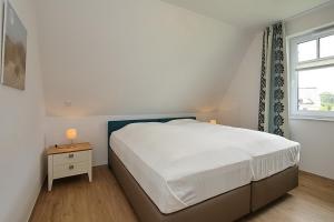 a bedroom with a white bed and a window at Reethaus Am Mariannenweg 12a in Boltenhagen
