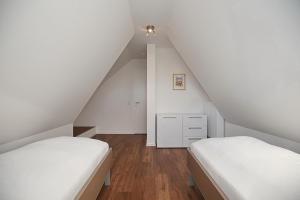 two beds in a attic bedroom with white walls at Reethaus Am Mariannenweg 06b in Boltenhagen
