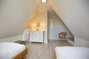 a attic bedroom with two beds and a dresser at Reethaus Am Mariannenweg 18b - Huus in Boltenhagen