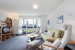 sala de estar con sofá verde y sillas en Godewind Wohnung 27 en Boltenhagen