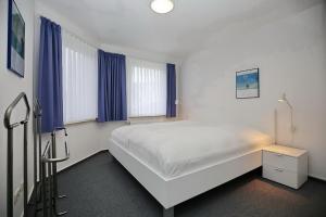 1 dormitorio con cama blanca y ventanas azules en Godewind Wohnung 27 en Boltenhagen