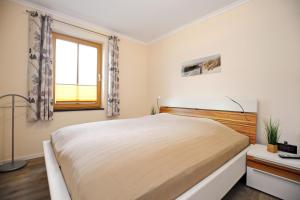 a white bedroom with a large bed and a window at Villa Sanddorn Wohnung 07 in Börgerende-Rethwisch