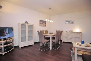 a dining room with a table and chairs and a tv at Sünnslag Wohnung 103 in Boltenhagen