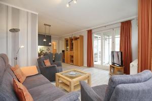 a living room with a couch and chairs and a tv at Dünenblick Wohnung 10 in Boltenhagen