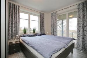 - une chambre avec un grand lit et 2 fenêtres dans l'établissement Dünenblick Wohnung 10, à Boltenhagen