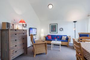 ein Wohnzimmer mit einem blauen Sofa und Stühlen in der Unterkunft Godewind Wohnung 21 in Boltenhagen