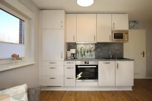 a kitchen with white cabinets and an oven at Urlauberdorf Haus 41d in Boltenhagen