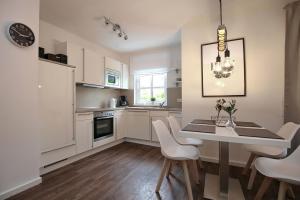 a kitchen with a table and chairs and a white refrigerator at Residenz von Flotow Wohnung 04 in Heiligendamm
