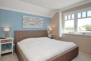 a bedroom with a large bed and two windows at Haus am Wald Wohnung Sonne in Wittenbeck
